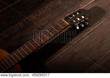 Classical Guitar Fretboard And Machine Head And Shadow On A Dark Wood Background With Negative Space