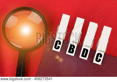Business Concept. On The Red Surface There Is A Magnifying Glass, A Notepad And Clothespins With The