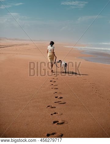 Young Woman Running And Playing With Dog At A Beach During Sunset, Hossegor Landes, France