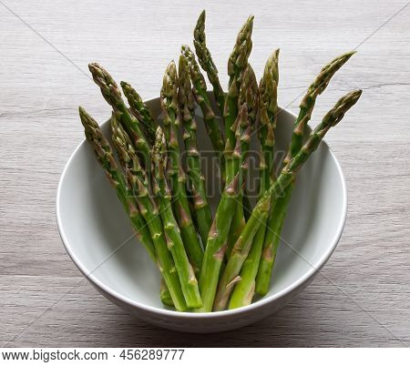 Fresh Asparagus In A Bowl Isolated On Wooden Background