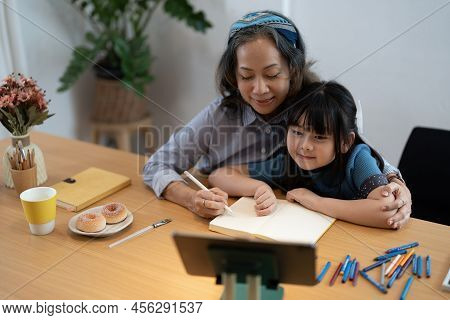 Smiling Senior Grandma And Cute Little Kid Granddaughter Watching Cartoons On Laptop Together, Happy