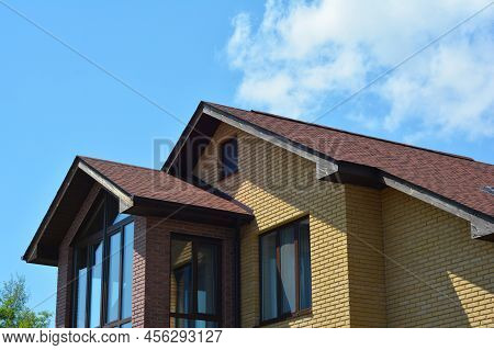 Brick House Rooftop With Panoramic Window And Asphalt Shingled Roof. Attic Skylight Window Wall.