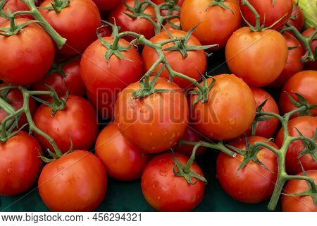 Closeup Of Pile Of Red Vine Tomatoes With Droplets Of Water On Farmers Market Stand