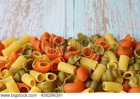 Heap Of Various Shapes Three-color Dried Vegeroni Pasta On Wooden Table