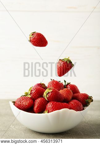 Strawberries Fall In Bowl On Light Background. Vertical Photo. Top View