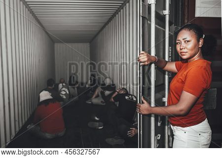 An African Women Opening The Door Of A Container, Inside Of Which Several People Were Sitting, To Hu
