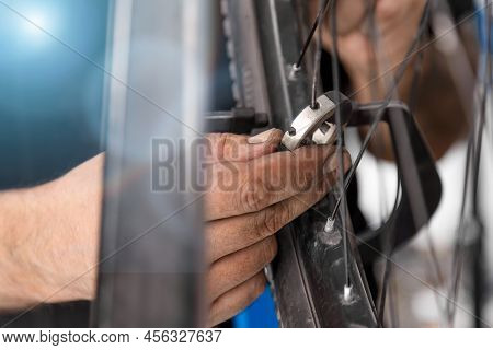 Using Spoke Wrench, An Experienced Bicycle Master Tightens The Spokes On The Wheel Of Bicycle Transp