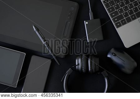 Stylus And Graphics Tablet With Screen On Black Background Next To Headphones, Laptop, Computer Mous