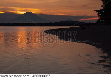 Bright Majestic Golden Sunset On Ocean With Dark Silhouette Volcano, Orange Saturated Reflection Of 