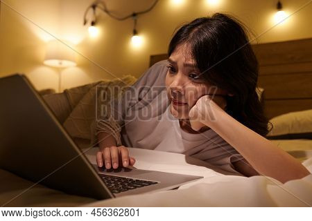Teenge Girl Reading Articles And Posts On Social Media When Resting On Bed With Laptop