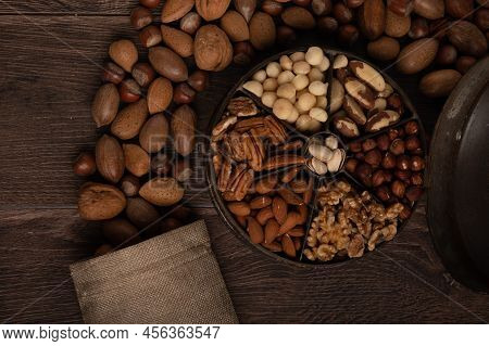 Mixed Nuts In A Tin And Burlap Sack Up Close On A Dark Wood Background