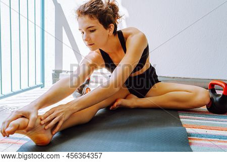 Young Woman Or Teenager Of Athletic Build Is Engaged In Stretching Muscles Of Legs Before Training. 