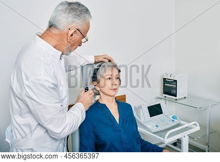 Mature Audiologist With Tympanometer Probe Doing Procedure Tympanometry Or Impedance Audiometry For 