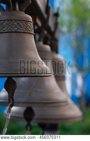 Several Church Bells, Bell Ringing On Blue Blurred Background. Bells Cast According To Old Recipe Fr