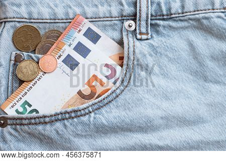 Banknotes Of 50, 20 And 10 Euros And Coins In The Pocket Of Light Blue Jeans. The Concept Of Solvenc