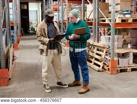African American Man Discussing Checklist With His Colleague While Standing In Store Before Shipping
