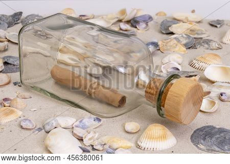 A Glass Bottle With A Note Inside On A Sandy Beach With Shells . A Folded Message In A Bottle 22