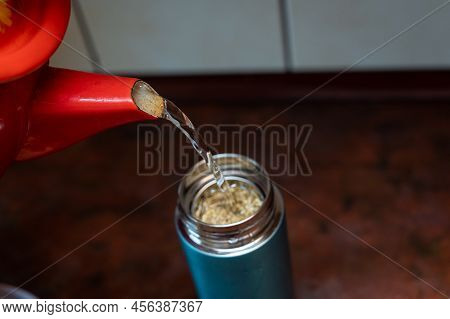 Boiling Water From The Red Chanter Is Poured Into A Thermos. The Teapot Is Filled With Medicinal Her