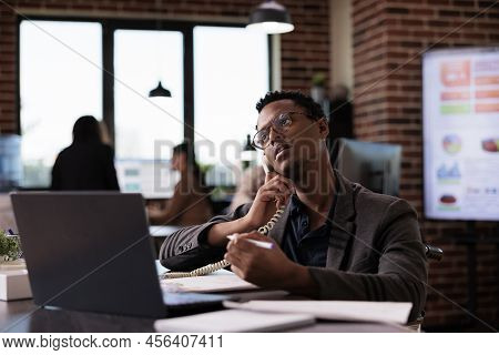 Male Secretary Wheelchair User Answering Landline Phone Call, Having Remote Conversation On Telephon
