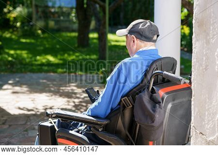 Lonely Senior Old Man In A Wheelchair Is Sitting Igarden Or Park. From Back Without Recognizable Fac