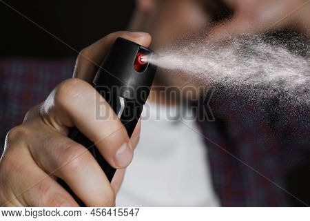 Man Covering Eyes With Hand And Using Pepper Spray, Closeup