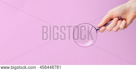 Magnifying Lens In Hand On Pink Ad Banner With Copy Space For Text. High Quality Photo