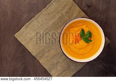 Bowl Of Tasty Carrot Cream Soup On Wooden Background
Carrot Soup With Fresh Parsley On Brown Table. 