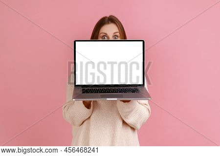 Portrait Of Blond Woman Holding Laptop In Hands, Covering Half Of Face With Notebook With Empty Disp