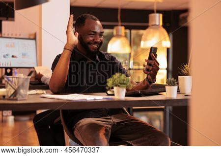African American Man Using Videocall Conference On Smartphone, Having Remote Conversation With Colle