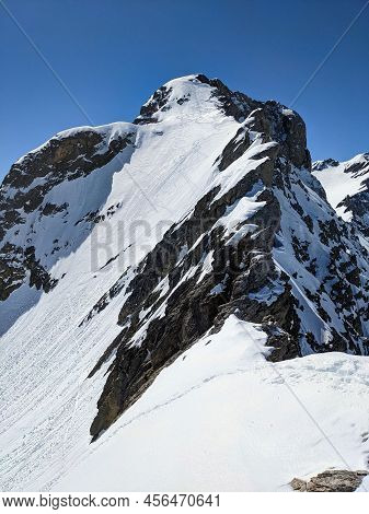 Steep Ascent To The Bocktschingel Mountain. Ski Mountaineering. With The Skis On Your Back To The Su