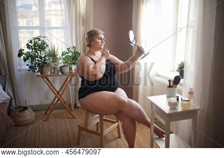 Overweight Woman Sitting And Looking At Mirror At Home, Selfcare Concept.