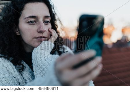Unhappy Young Woman Resting And Sitting On The Roof With City View And Taking Selfie.