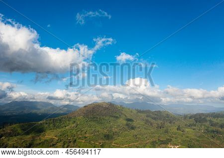 Aerial View Of Green Tea Plantation Against The Blue Sky And Clouds In The Mountains. Tea Estate Lan