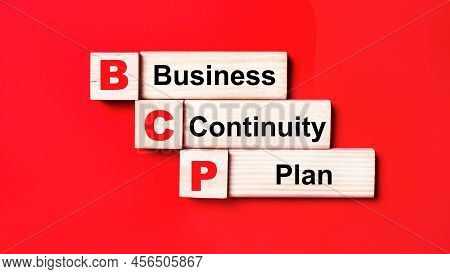 On A Bright Red Background, Wooden Cubes And Blocks With The Text Bcp Business Continuity Plan. Manu