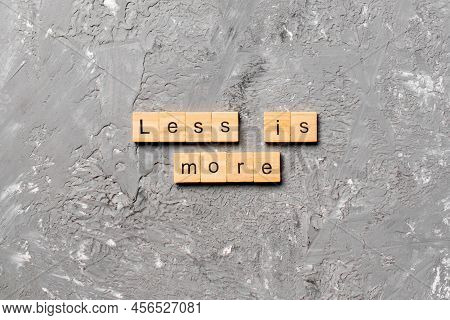 Less Is More Word Written On Wood Block. Less Is More Text On Table, Concept.