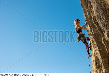 The Girl Climbs The Rock. The Climber Trains On Natural Terrain.  A Woman Overcomes A Difficult Clim