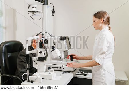 Doctor Examines Elderly Mans Eye On Screen Of Autorefractometer.