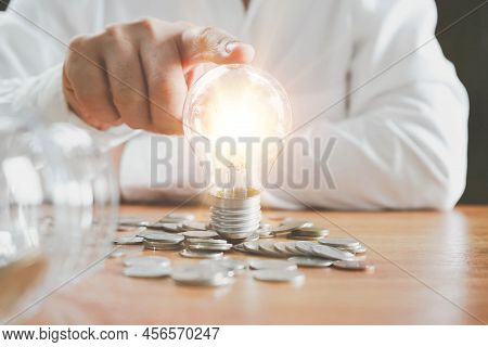 Saving Energy And Money Concept. Idea For Save Or Investment. Businessman Touching A Bright Light Bu