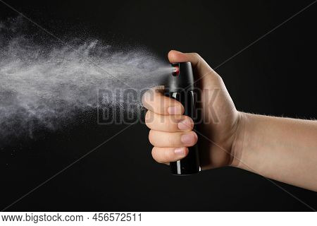 Man Using Pepper Spray On Black Background, Closeup