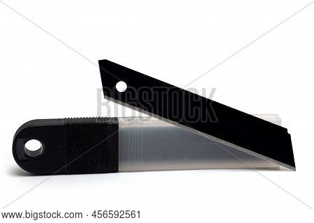 Close Up Of Plastic Package And Dark Sharp Metal Razor Blade Placed In Front Of It For Use In Knives