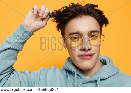 A Close Portrait Of A Funny Man Standing On An Orange Background In Bright Sunglasses Looking At The
