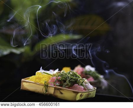 Balinese Offering With Incense Smoke Swirling Above. Canang Sari Filled With Flower Petals, Shredded