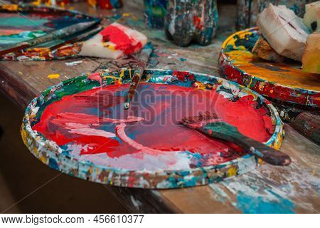 Bright Spots Of Paint In An Art Workshop With Brushes