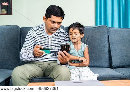Father And Daughter Online Shopping By Using Credit Card Payment On Mobile Phone At Home - Concept O