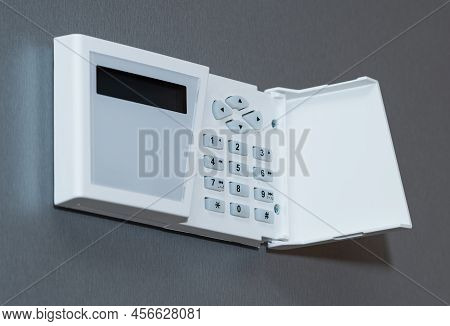 Security System Keyboard With Buttons And Plastic Cover Mounted On A Gray Textured Wall.