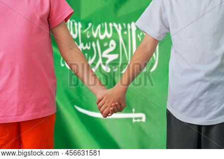 Two Children Joined Hands On Flag Saudi Arabia Background. Boy And Girl Joined Hands On Background F