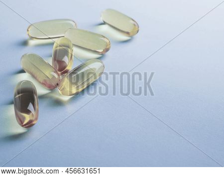Fish Oil Softgels. Vitamins And Healthy Lifestyle. Blue And Yellow Tinted Background. Pale Backdrop 