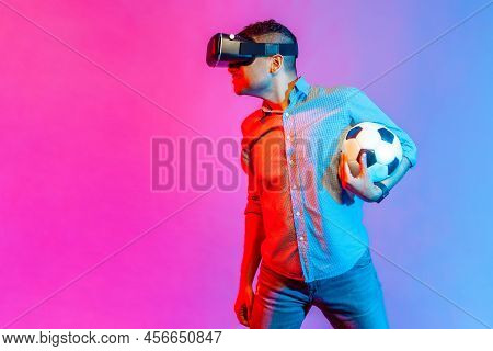 Portrait Of Man In Shirt Standing With Soccer Ball, Wearing Virtual Reality Glasses, Looking Attenti