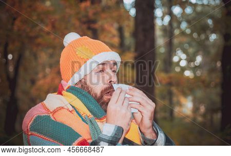 Mature Man In Jacket Suffering From Cold. Blowing Nose With A Tissue, Looking Miserable Unwell Very 