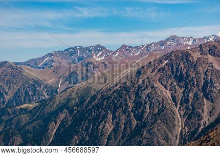 Rocky Snow-capped Mountains Under The Sun And Blue Sky